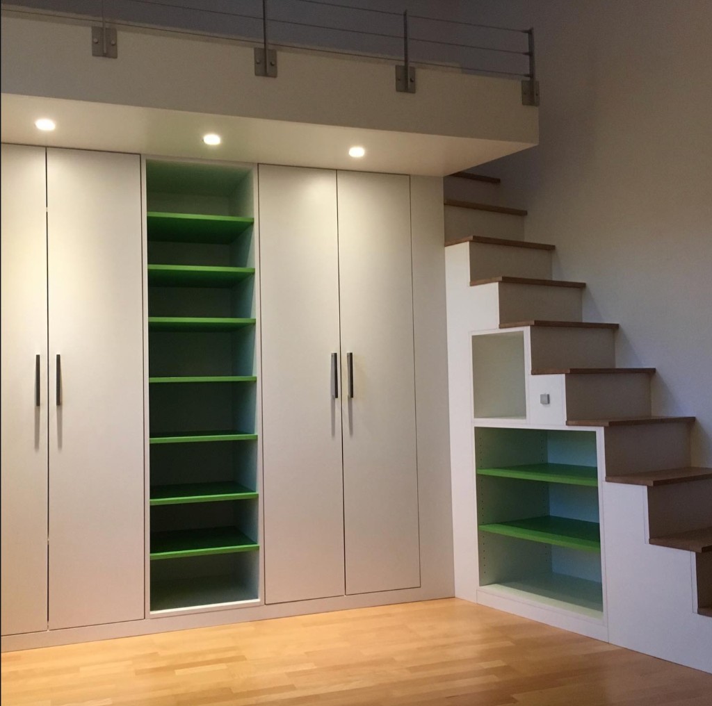 Einbauschrank mit farbigen Regalen und integrierter Treppe