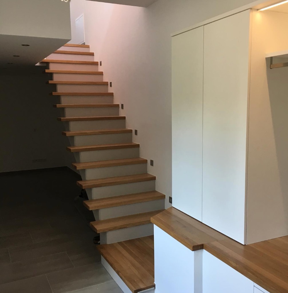 Weiße Treppe mit Holzstufen und Einbaumöbel