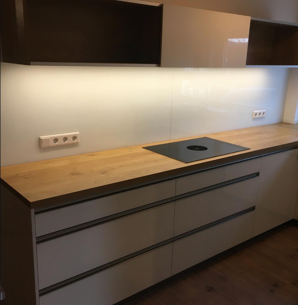 Küchendetail mit Holzplatte, Glasnischenrückwand und Kochfeld